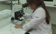 Dziewczynka w fartuchu przy mikroskopie