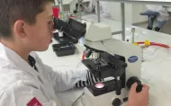 Chłopiec w fartuchu przy mikroskopie